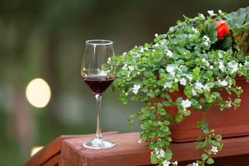 A glass of red wine at a picnic near a flower bed, tasting