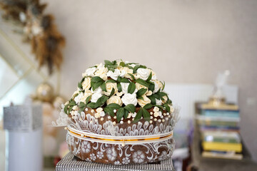 A stylish wedding cake made of baked flowers and green leaves.