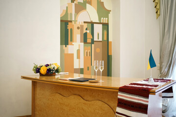 Hall of wedding ceremonies with a table with glasses, a book and a Ukrainian flag.