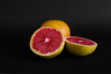 still life food two halves of red grapefruit on black background isolated close-up