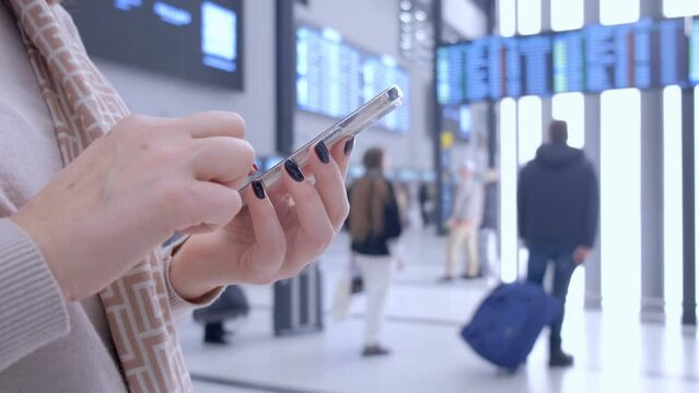 Close-up. People in international airport. Female traveler look at phone, search for boarding pass or flight cancelation information. 4K