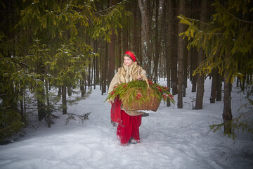 Teen girl in thick coat and a red sash with basket of fir branches and berries in cold winter day...