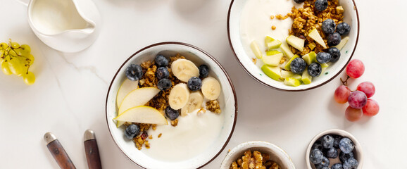 Weight loss, healthy lifestyle and eating. Two healthy breakfast bowl with ingredients granola fruits Greek yogurt and berries on white background top view - obrazy, fototapety, plakaty
