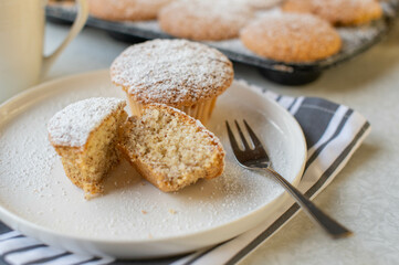 Gluten free muffins with almonds on a plate with cross section view and muffin tin in the background
