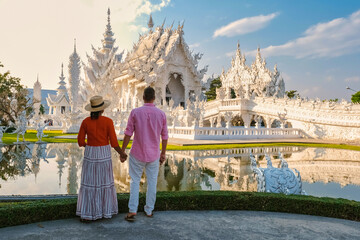 The White Temple Chiang Rai during sunset, Evening view of Wat Rong Khun or White Temple, a Landmark in Chiang Rai, A couple of men and woman visiting the white temple during vacation in Thailand - obrazy, fototapety, plakaty