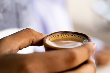 Hot milk tea or chai in traditional kulhad or clay pot or earthen cup held by hand. This is very...