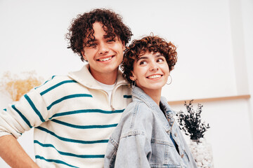 Obraz premium Smiling beautiful woman and her handsome boyfriend with curls hairstyle. Happy cheerful family having tender moments in white interior in studio.Pure cheerful models hugging. Embracing each other