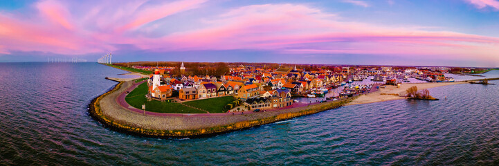 Urk Netherlands, an Old historical harbor and lighthouse at sunset, a Small town of Urk village with beautiful colorful streets and houses alongside the harbor by the lake Ijsselmeer in Flevoland - obrazy, fototapety, plakaty