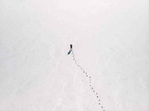 Aerial view a person standing on an empty salt flat with footprints leading up to the person, South Australia.