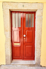Old traditional wooden door with wrought iron door knockers on white facade in Portugal