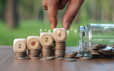 The word 2024 in a wooden block is placed on a coin and a human hand holds a wooden block. Ideas to start the new year with business and green business saving money investing in green business in 2024