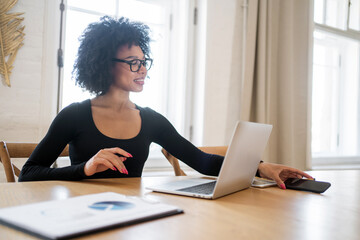 A young woman freelancer courses in finance curly training online video call uses a laptop computer. A happy employee of the company is busy working alone in the office.