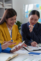 Asian business colleagues present and discuss investment project work and planning strategies. Budget calculation Income from documents reporting the company's business growth.