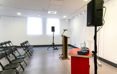 Modern and luminous room, empty, prepared for an event. Lectern with microphone and sound system...