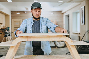 Carpenter works with wood in carpentry workshop. Man doing woodwork professionally