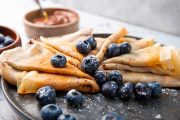 Thin pancakes with chocolate spread and blueberries on the table close up