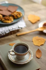 Fotobehang Cup of tea or coffee, plate with desserts, dried oranges, bowl of grapes, scented candles, vintage books, pumpkins and autumn leaves on the table. Autumnal hygge. Selective focus. © jelena990