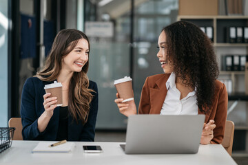 female colleague of half descent holds a cup of coffee and smiles happily.