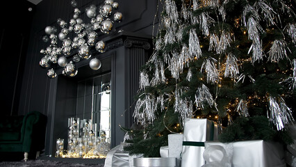 Christmas tree with modern silver decorations and gifts at home. New Year decoration and festive Christmas mood. Christmas tree with stylish decor.