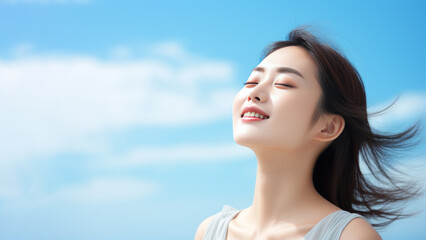 A Asian woman breathes calmly looking up isolated on clear blue sky - obrazy, fototapety, plakaty