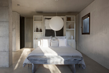 Modern bedroom of a designer farmhouse with a double bed with lots of pillows and large windows...