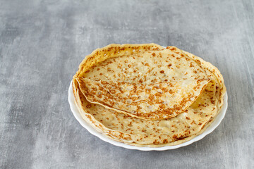 Fresh baked french crepes or Russians blinis on grey background