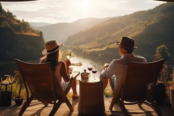 Adult couple siting on chairs at terrace and drink wine in the mountains at summer - Powered by Adobe