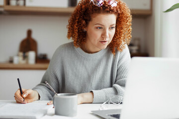 Portrait of attractive redhead caucasian businesswoman in casual clothes working from home, making...