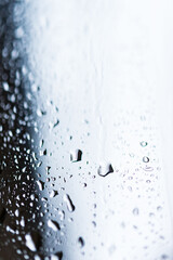 Plan serré d'une fenêtre avec gouttes d'eau de pluie en noir et blanc, mise au point sur une goutte, atmosphère mélancolique. - obrazy, fototapety, plakaty