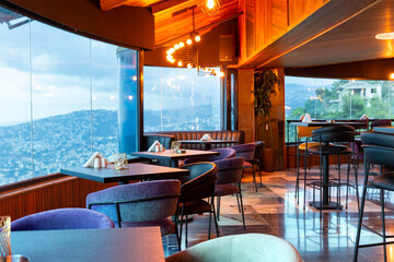 Interior of cozy restaurant with panoramic windows. Tables for four guests