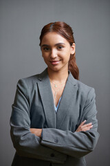 Portrait of young confident female entrepreneur standing against grey background