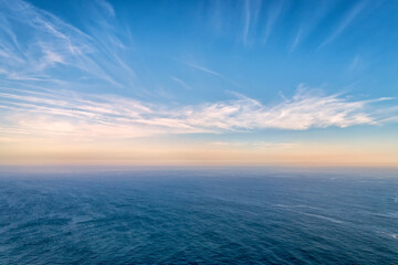 Beautiful seascape at sundown, clouds and calm sea waves, clear blue