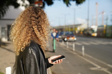 woman walking in the street and checking phone waiting for taxi