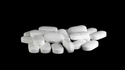 Pile of Sertraline 100mg pills on black background