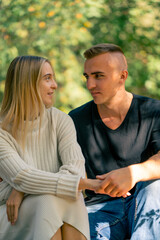 Obraz premium A young couple a guy and a girl are talking seriously while sitting together on sunny day in nature