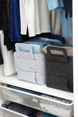 Felt baskets for storing things. Two felt boxes in the closet with neatly folded jeans and sweaters. Home storage system