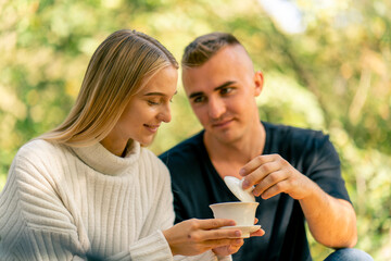 Close-up shot of a smiling couple in love relaxing together and tasting natural tea during tea ceremony in nature