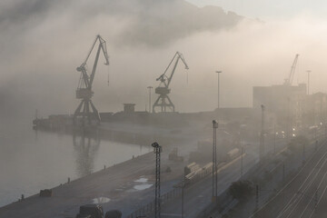 industrial area of the port of Pasaia (Spain) with port cranes in the morning fog - 674512124