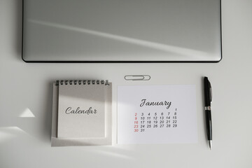 Top view of workplace with january calendar and laptop