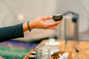 Close-up shot of the hand of a tea master passing a bowl of natural tea to a girl at tea ceremony
