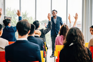 In a boardroom strategy session businesspeople participate in a meeting and seminar. Hands raised...