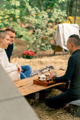 A young couple a guy and a girl are sitting at a tea ceremony and listening carefully to tea master brewing natural tea