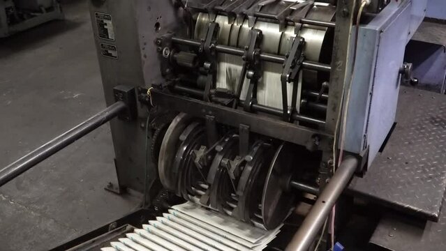 Working old printing machine printing newspaper in typographical printing house.