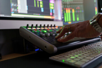 A sound engineer's hand adjusting sliders on an audio mixing console, showcasing the technical side of music production and mixing precision.
