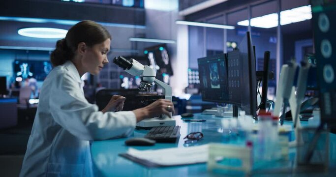 Medicine Development Laboratory: Caucasian Female Scientist Using Microscope, Analyzes Petri Dish Sample. Pharmaceutical Lab with Specialists Conducting Biotechnology Research, Developing New Drugs.