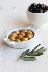 Green and black  olives, olive oil and olive leaves on a white background