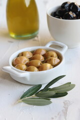 Green and black  olives, olive oil and olive leaves on a white background
