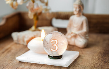 Number three on Gemstone sphere or crystal balls known as crystallum orbis and orbuculum. Natural clear quartz ball on stand on wood tray in home. Predictions concept.