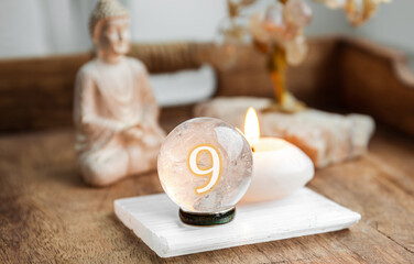 Number nine on Gemstone sphere or crystal balls known as crystallum orbis and orbuculum. Natural clear quartz ball on stand on wood tray in home. Predictions concept.