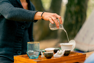 Fototapeta na wymiar A man's hand pours boiling water into ceramic bowls for making tea at tea ceremony masterclass